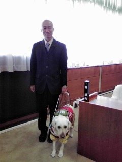 会長 林道夫と、寄り添う盲導犬イオの写真
